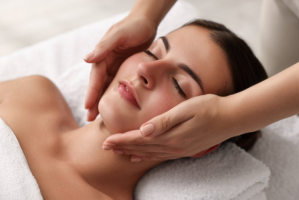 A person receiving a facial massage with light skincare product applied to the face.